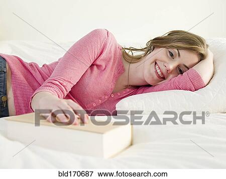 Caucasian woman with book laying on bed View Large Photo Image Stock Photo - Caucasian woman with book laying on bed. Fotosearch