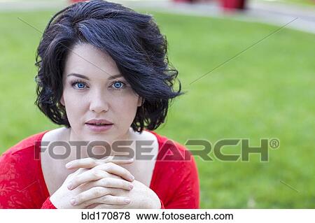 Stock Photo - Caucasian woman with hands clasped in grass. Fotosearch