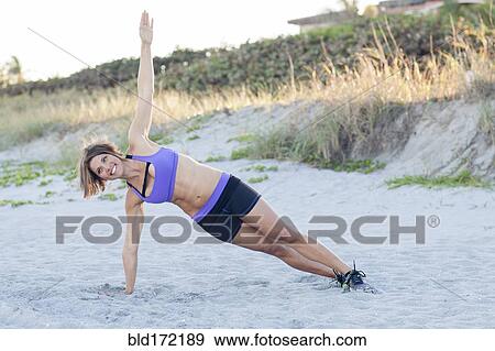 Stock Photo - Caucasian woman working out on beach. Fotosearch