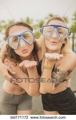 Stock Image - Caucasian women blowing kisses in snorkel masks. Fotosearch