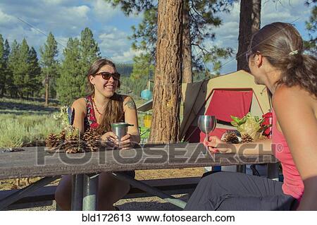 Stock Image - Caucasian women drinking wine at campsite. Fotosearch