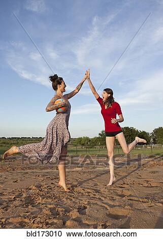 Stock Image - Caucasian women high fiving in rural field. Fotosearch