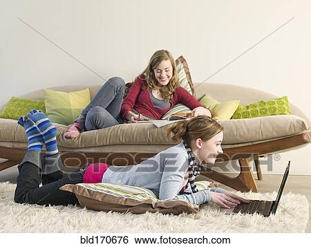 Stock Photograph - Caucasian women reading in living room. Fotosearch
