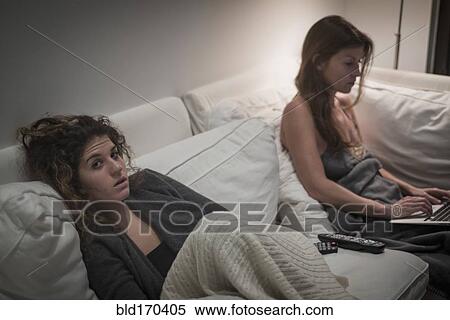 Stock Photography - Caucasian women sitting on sofa at night. Fotosearch