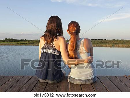 Caucasian women sitting on wooden dock over lake View Large Photo Image Stock Image - Caucasian women sitting on wooden dock over lake. Fotosearch