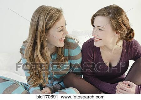Stock Image - Caucasian women smiling on bed. Fotosearch