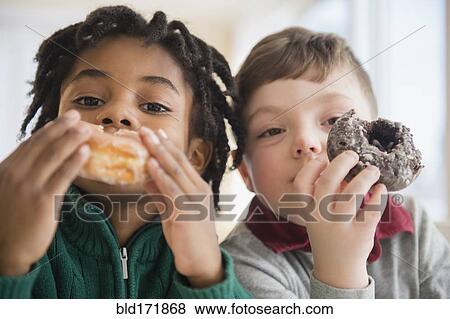 Stock Photo - Close up of boys eating donuts. Fotosearch
