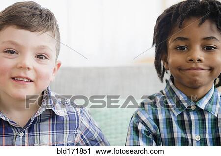 Stock Image - Close up of boys smiling on sofa. Fotosearch