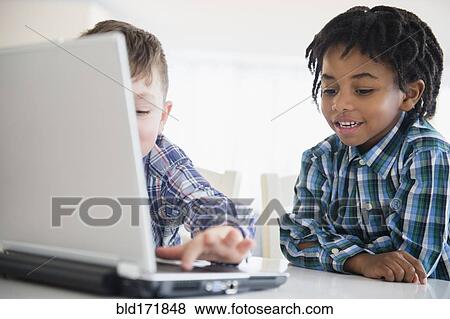 Stock Photo - Close up of boys using laptop at desk. Fotosearch