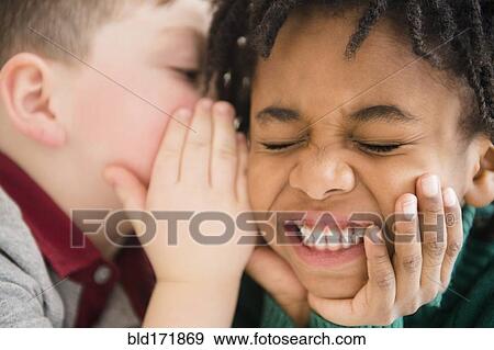 Stock Photo - Close up of boys whispering secrets. Fotosearch