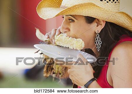 Picture - Close up of Hispanic woman eating corn. Fotosearch