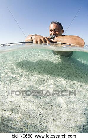 Close up of man laying on surfboard in ocean View Large Photo Image Stock Image - Close up of man laying on surfboard in ocean. Fotosearch