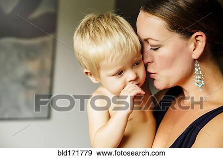 Stock Photo - Close up of mother holding son in living room. Fotosearch