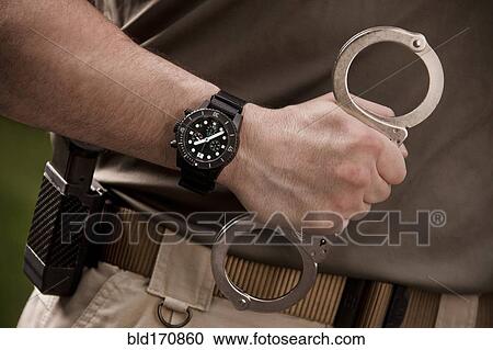Close up of police officer holding handcuffs View Large Photo Image Stock Image - Close up of police officer holding handcuffs. Fotosearch