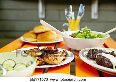 Stock Image - Close up of salad, meat, cucumbers and salad on table. Fotosearch