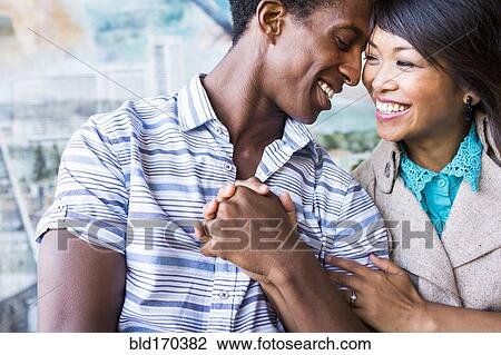 Stock Image - Close up of smiling couple holding hands. Fotosearch