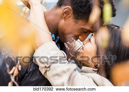 Close up of smiling couple hugging in autumn leaves View Large Photo Image Stock Image - Close up of smiling couple hugging in autumn leaves. Fotosearch