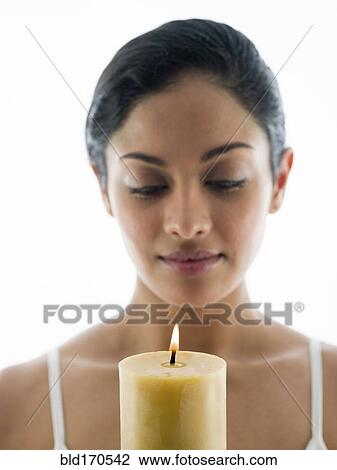 Stock Image - Close up of woman admiring candle. Fotosearch