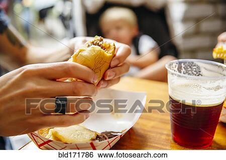 Stock Photograph - Close up of woman eating burger in restaurant. Fotosearch