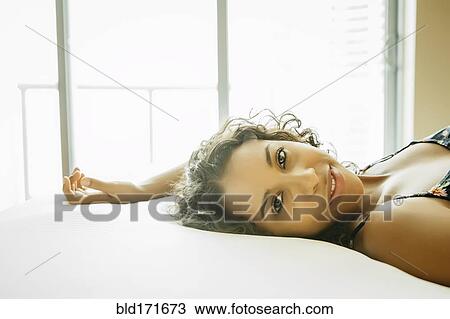 Stock Image - Close up of woman laying on hotel bed. Fotosearch
