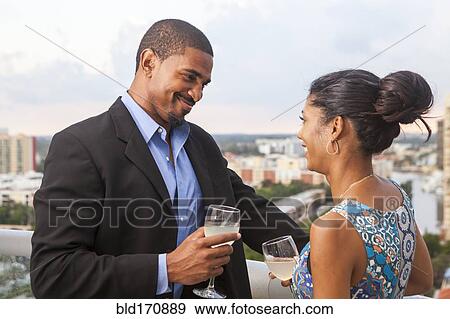 Stock Photo - Couple drinking wine on urban balcony. Fotosearch