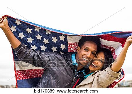 Stock Photo - Couple holding American flag quilt outdoors. Fotosearch