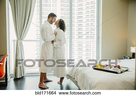 Picture - Couple hugging in bathrobes in hotel room. Fotosearch