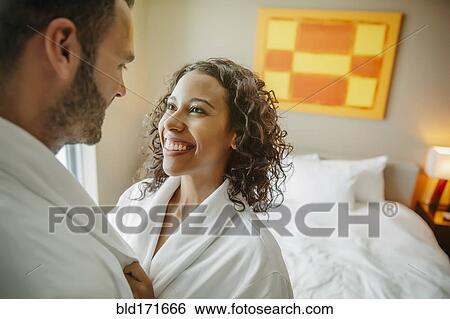 Stock Photograph - Couple hugging in bathrobes in hotel room. Fotosearch