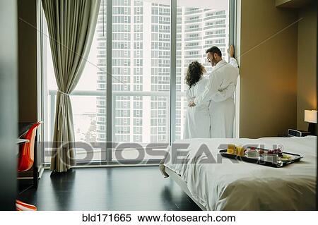 Stock Photography - Couple hugging in bathrobes in hotel room. Fotosearch