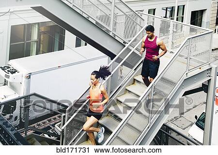 Stock Image - Couple jogging on city steps. Fotosearch