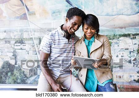 Stock Image - Couple sharing digital tablet by mural. Fotosearch