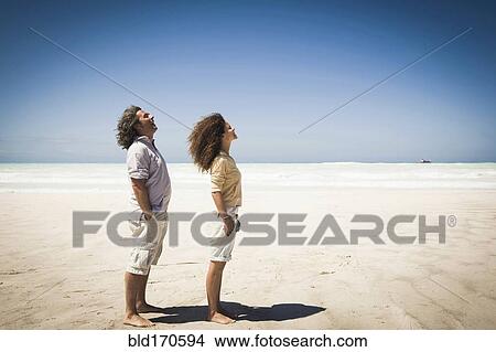 Picture - Couple standing in wind on beach. Fotosearch