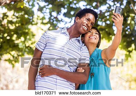 Couple taking selfie with cell phone outdoors View Large Photo Image Stock Image - Couple taking selfie with cell phone outdoors. Fotosearch