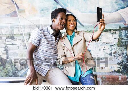 Stock Image - Couple taking selfie with digital tablet by mural. Fotosearch