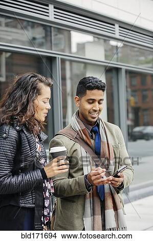 Picture - Couple using cell phone in city. Fotosearch