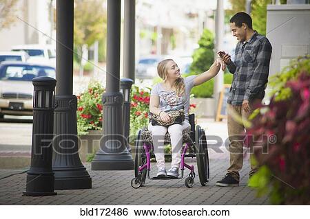 Stock Photograph - Couple using cell phone on city sidewalk. Fotosearch
