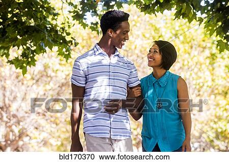 Stock Image - Couple walking arm-in-arm outdoors. Fotosearch