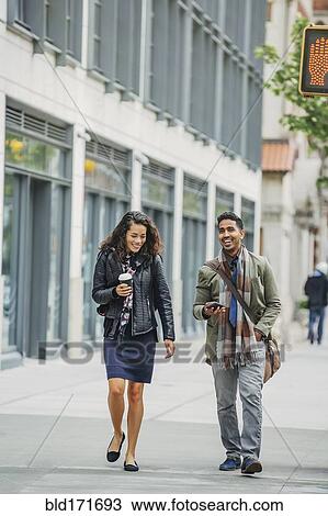 Couple walking on city sidewalk View Large Photo Image Stock Image - Couple walking on city sidewalk. Fotosearch