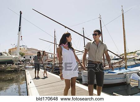 Couple walking on wooden dock in urban harbor View Large Photo Image Stock Photo - Couple walking on wooden dock in urban harbor. Fotosearch