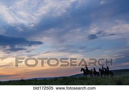 Stock Photography - Cowgirls and cowboy riding horses in rural field. Fotosearch