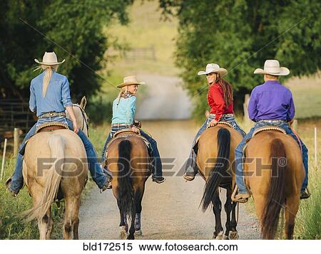 Stock Photography - Cowgirls and cowboy riding horses in rural road. Fotosearch