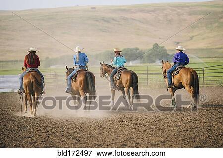 Stock Photo - Cowgirls and cowboy riding horses on ranch. Fotosearch