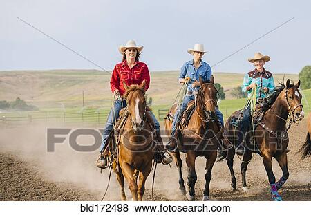 Stock Photo - Cowgirls riding horses on ranch. Fotosearch