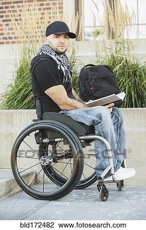 Stock Image - Disabled student in wheelchair reading book. Fotosearch