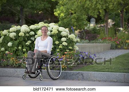 Stock Image - Disabled woman sitting in wheelchair on city street. Fotosearch