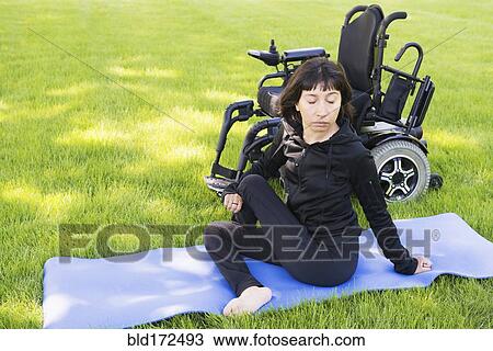 Stock Image - Disabled woman stretching legs in park. Fotosearch