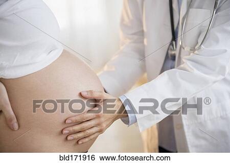 Stock Photograph - Doctor examining belly of pregnant woman. Fotosearch