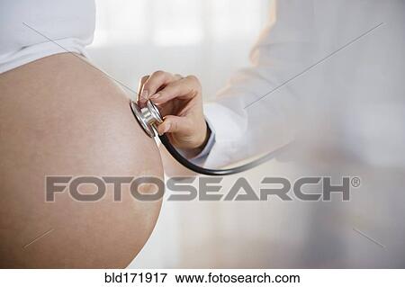 Doctor listening to belly of pregnant woman with stethoscope View Large Photo Image Stock Photo - Doctor listening to belly of pregnant woman with stethoscope. Fotosearch