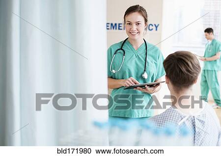 Stock Image - Doctor talking to patient in hospital emergency room. Fotosearch