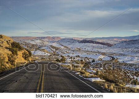 Stock Image - Empty road through snowy remote landscape, Moab, Utah, United States. Fotosearch